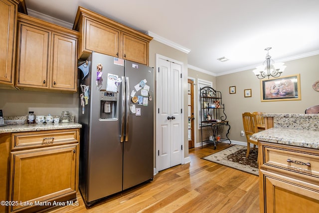 kitchen with an inviting chandelier, light wood-style floors, stainless steel fridge, crown molding, and baseboards