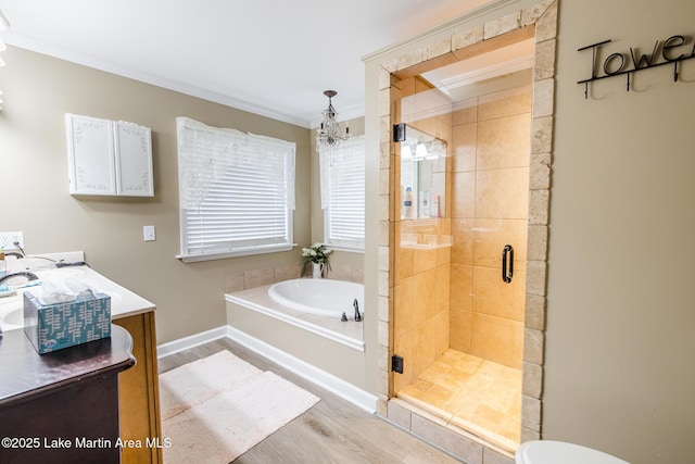 bathroom with wood finished floors, vanity, a stall shower, a garden tub, and crown molding