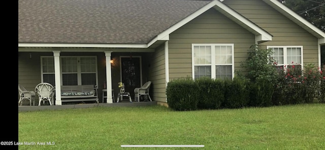 view of front of property with a front yard, a porch, and a shingled roof