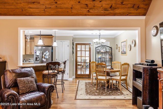 dining room with ornamental molding, light wood-style flooring, a chandelier, and baseboards