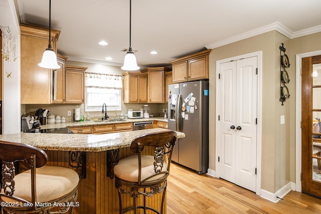 kitchen with appliances with stainless steel finishes, a peninsula, light wood-type flooring, and a sink