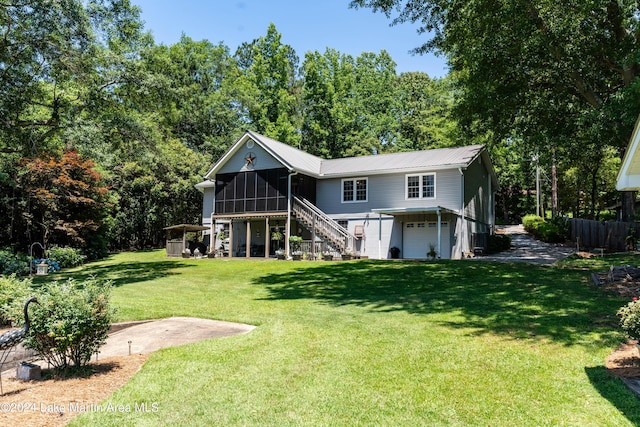 rear view of house with a lawn, a sunroom, and a garage