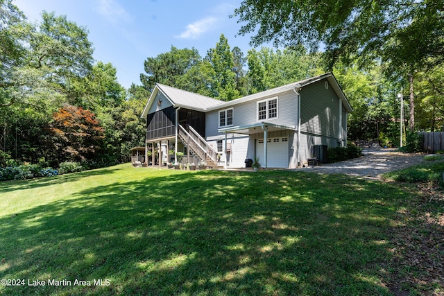 back of house featuring a sunroom, a garage, and a yard