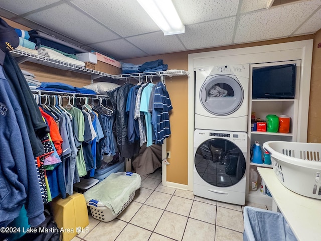 laundry room with stacked washer / dryer and tile patterned flooring