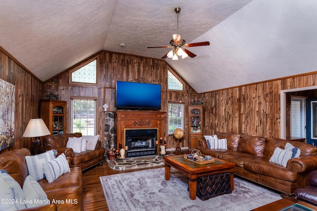 living room with a textured ceiling, hardwood / wood-style flooring, ceiling fan, and wood walls