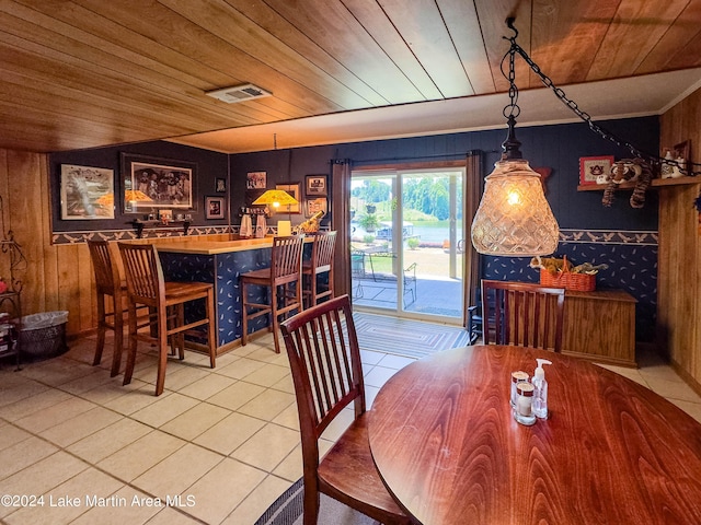 dining area featuring tile patterned floors, wooden ceiling, and wood walls