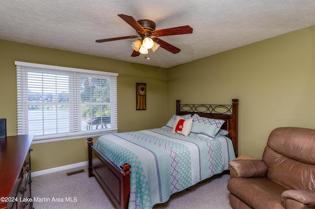 carpeted bedroom featuring a textured ceiling and ceiling fan