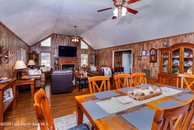 dining space featuring a textured ceiling, ceiling fan, wood walls, and hardwood / wood-style flooring