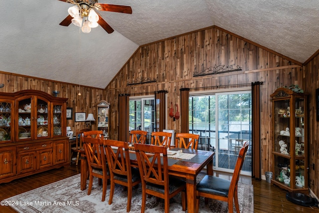 dining room with dark hardwood / wood-style flooring, a textured ceiling, and wood walls