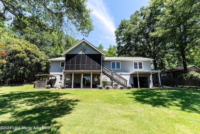 rear view of property featuring a carport, a lawn, and a sunroom