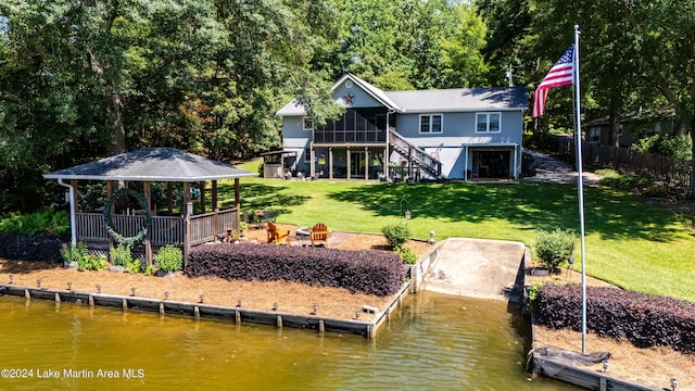 back of house with a lawn, a sunroom, and a water view