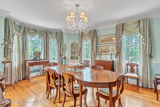 dining space featuring a healthy amount of sunlight, an inviting chandelier, ornamental molding, and light hardwood / wood-style flooring