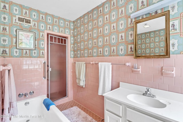 bathroom featuring vanity, independent shower and bath, and tile walls