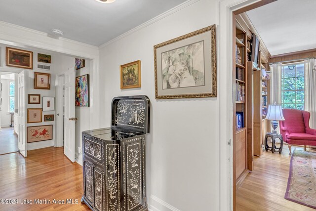 hallway with light hardwood / wood-style flooring and ornamental molding