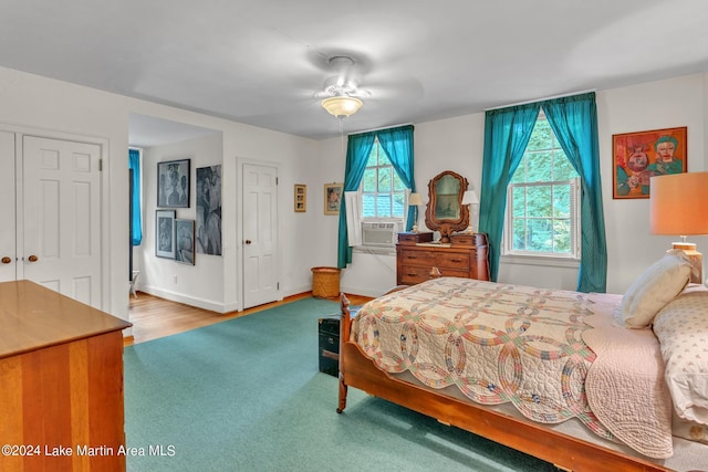 bedroom featuring ceiling fan, cooling unit, and wood-type flooring