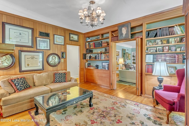 sitting room with wood walls, built in features, light wood-type flooring, and an inviting chandelier