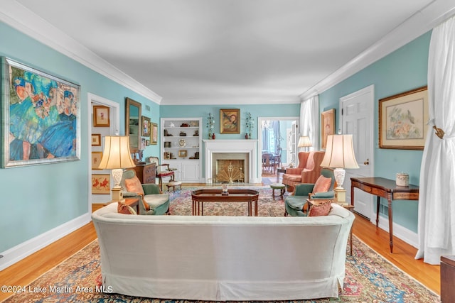 living room with built in shelves, crown molding, and light hardwood / wood-style flooring