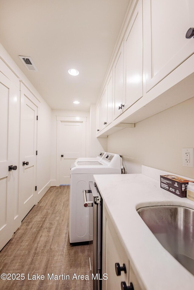 1220 Willow Way E, Alexander City, AL 35010 - laundry room featuring a sink, separate washer and dryer, visible vents, light wood-style floors, and cabinet space
