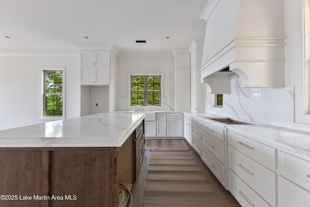 kitchen with dark wood-style flooring, white cabinets, a kitchen island, and tasteful backsplash
