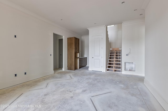unfurnished room with concrete flooring, baseboards, ornamental molding, and stairway