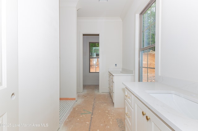 bathroom with baseboards, a sink, crown molding, and two vanities