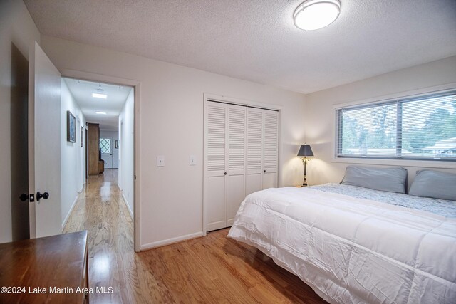 bedroom featuring a closet, a textured ceiling, and light wood-type flooring