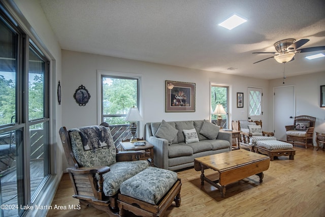 living room with ceiling fan, light hardwood / wood-style floors, and a textured ceiling