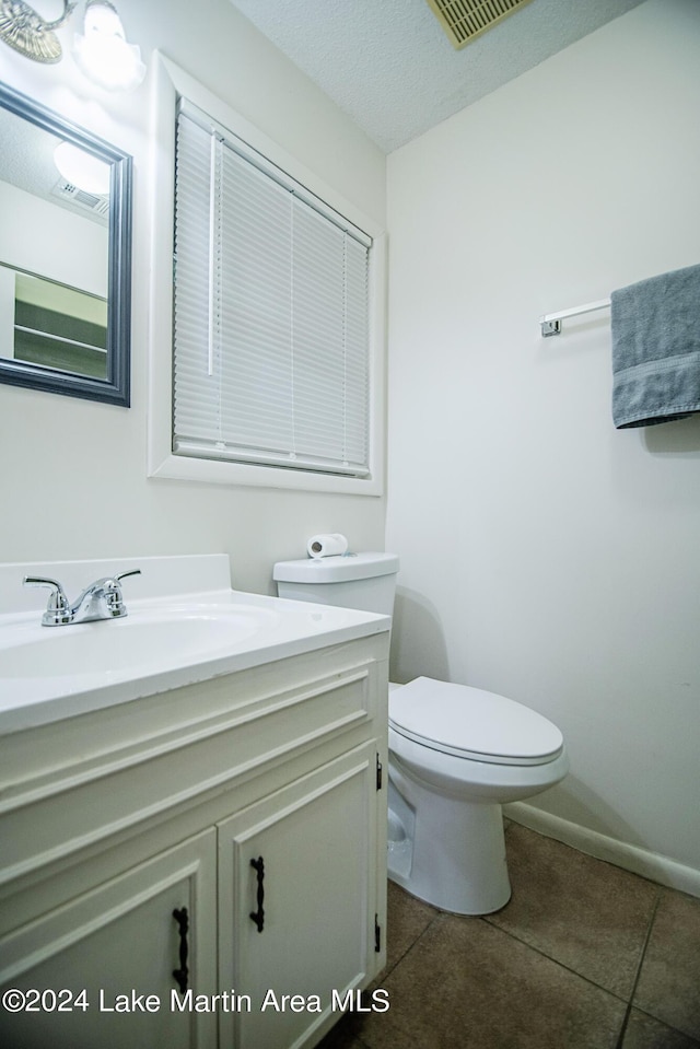 bathroom with tile patterned flooring, vanity, toilet, and a textured ceiling