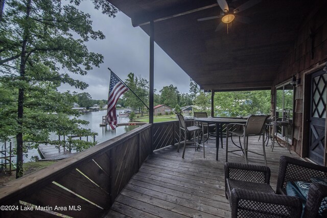 wooden deck with ceiling fan and a water view