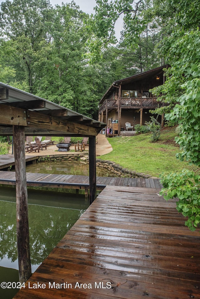 view of dock with a yard and a water view