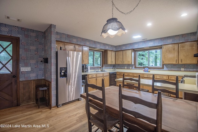 kitchen featuring a wealth of natural light, stainless steel fridge with ice dispenser, pendant lighting, and light wood-type flooring