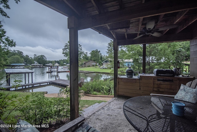 exterior space with a boat dock, an outdoor kitchen, a water view, and ceiling fan