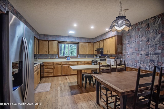 kitchen featuring a textured ceiling, pendant lighting, light wood-type flooring, and appliances with stainless steel finishes