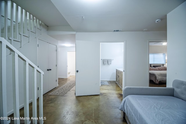 bedroom with concrete flooring, connected bathroom, and a closet