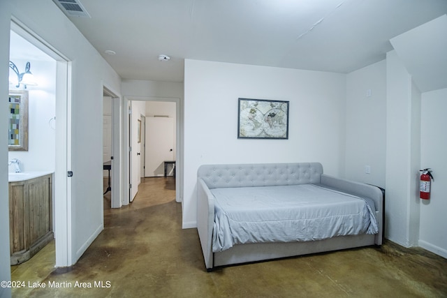 bedroom with ensuite bathroom, sink, and concrete floors