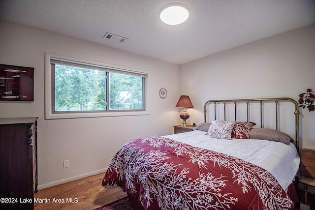 bedroom with wood-type flooring and a textured ceiling