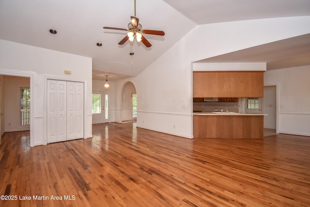 1647 Timber Trl, Alexander City, AL 35010 - unfurnished living room with high vaulted ceiling, a ceiling fan, a sink, arched walkways, and light wood finished floors
