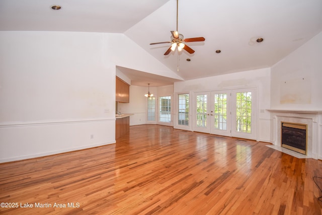 1647 Timber Trl, Alexander City, AL 35010 - unfurnished living room with light wood finished floors, french doors, a premium fireplace, high vaulted ceiling, and ceiling fan with notable chandelier
