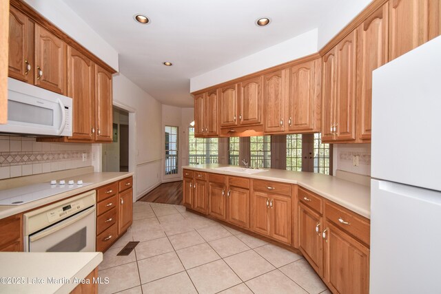 1647 Timber Trl, Alexander City, AL 35010 - kitchen with backsplash, light countertops, a sink, light tile patterned flooring, and white appliances