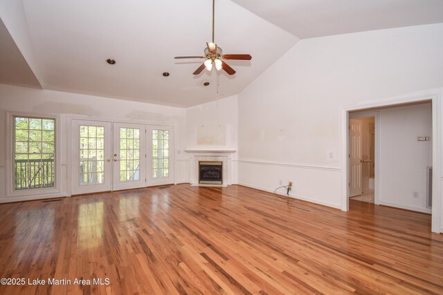 1647 Timber Trl, Alexander City, AL 35010 - unfurnished living room with high vaulted ceiling, a ceiling fan, light wood-type flooring, a fireplace with flush hearth, and french doors