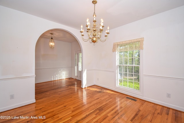 1647 Timber Trl, Alexander City, AL 35010 - empty room with arched walkways, wood finished floors, visible vents, and an inviting chandelier