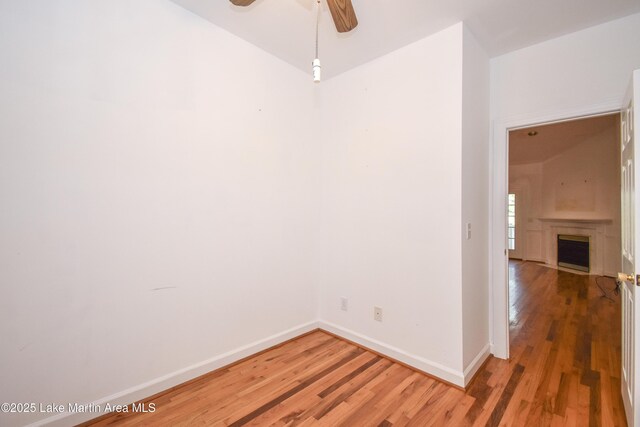 1647 Timber Trl, Alexander City, AL 35010 - spare room featuring ceiling fan, baseboards, a fireplace, and light wood-style flooring