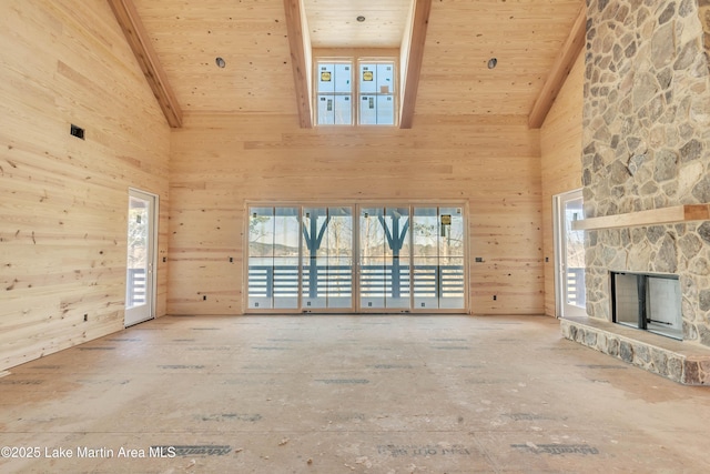 unfurnished living room with wood ceiling, wood walls, vaulted ceiling with beams, and a stone fireplace