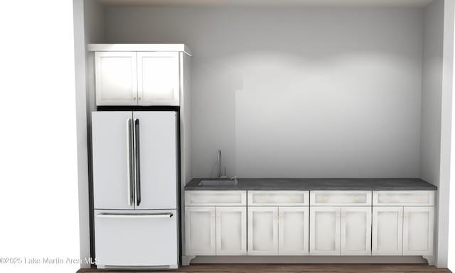 kitchen with dark countertops, a sink, and freestanding refrigerator