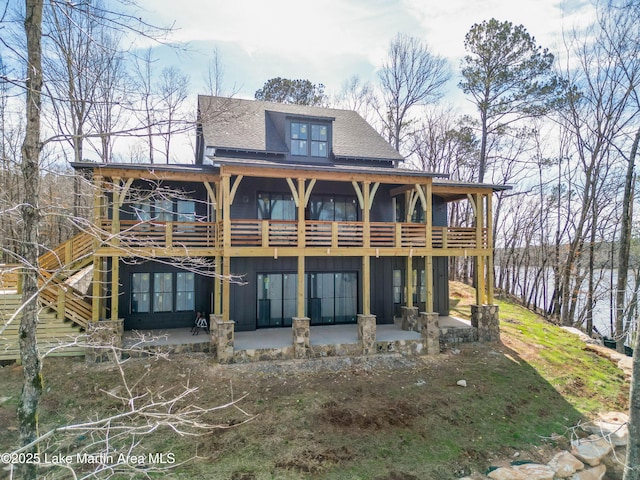 rear view of property featuring a shingled roof, board and batten siding, and a patio area