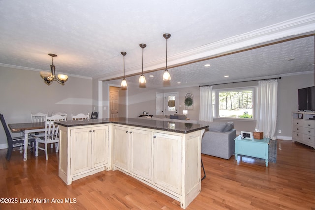 241 Warrior Rd, Alexander City, AL 35010 - kitchen with light wood finished floors, crown molding, open floor plan, pendant lighting, and a notable chandelier