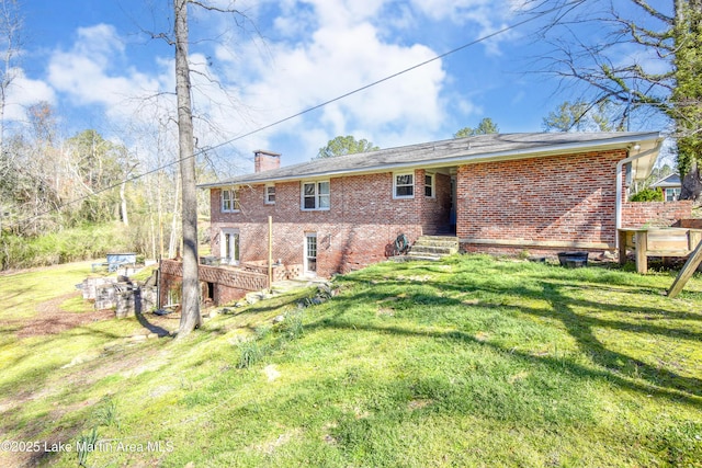 241 Warrior Rd, Alexander City, AL 35010 - rear view of house with brick siding, a lawn, and a chimney