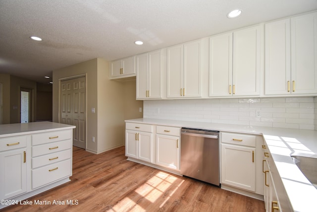 kitchen with backsplash, stainless steel dishwasher, white cabinetry, and light hardwood / wood-style flooring