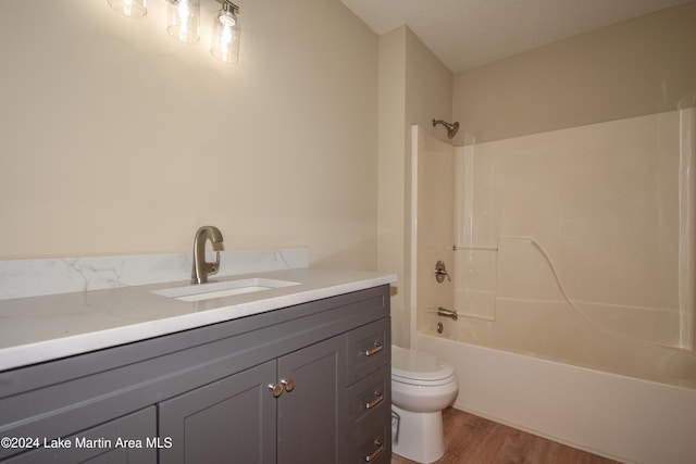 full bathroom featuring a textured ceiling, washtub / shower combination, vanity, toilet, and hardwood / wood-style flooring