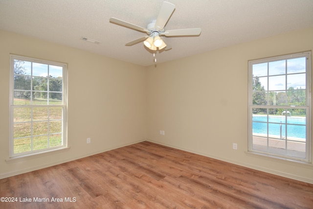 empty room with light hardwood / wood-style flooring, a water view, and ceiling fan